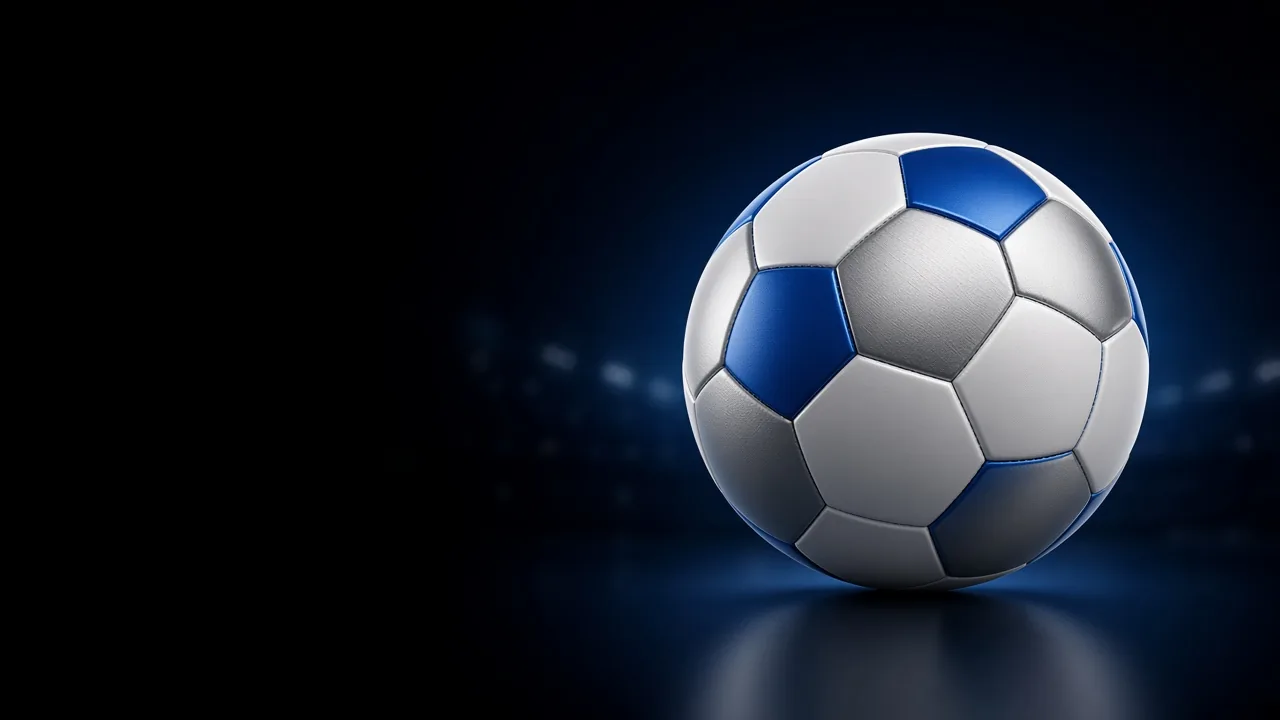 A blue and white football on a dark ground, with stadium lights blurred behind